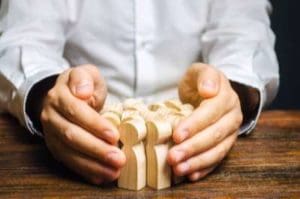 image of mans hands around wooden people